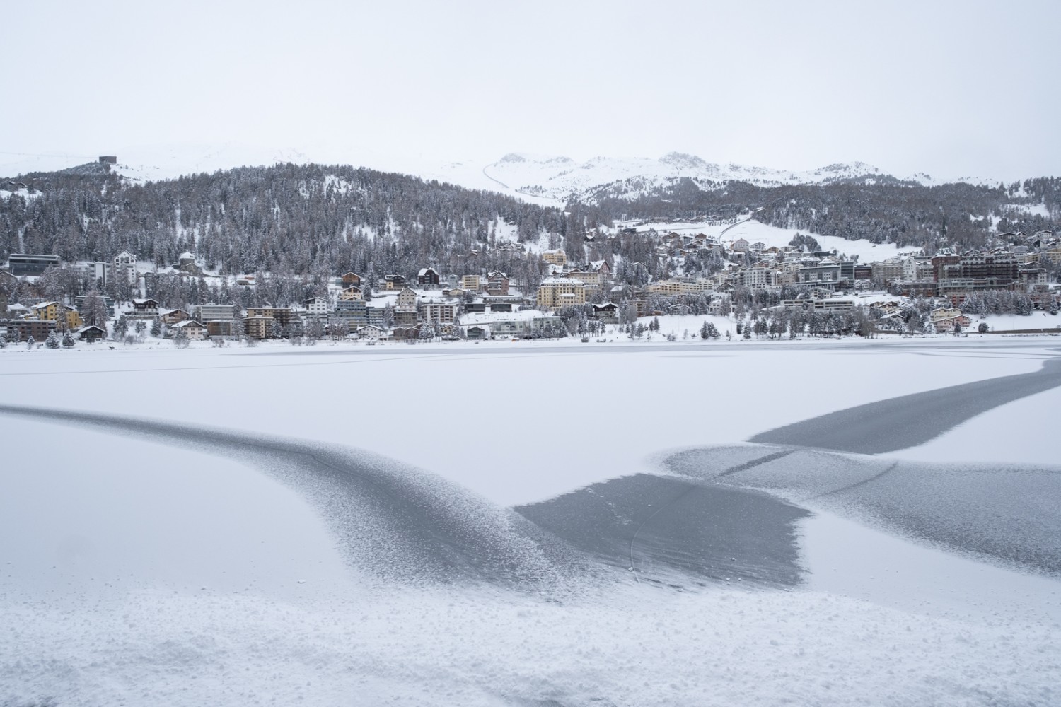 Eisiger Blick vom Ufer des St. Moritzersees auf St. Moritz. 