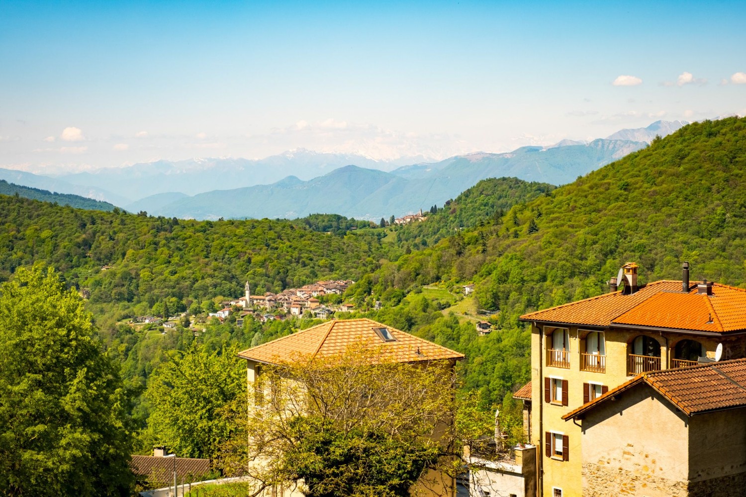Curio und Bedigliora im Vordergrund. Im Hintergrund der Monte Rosa im Dunst.